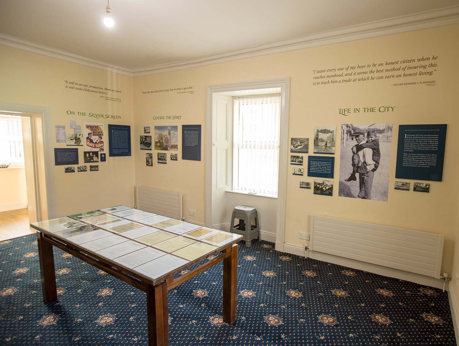Interior view of Father Flanagan Visitor Centre showing exhibits on walls and table.