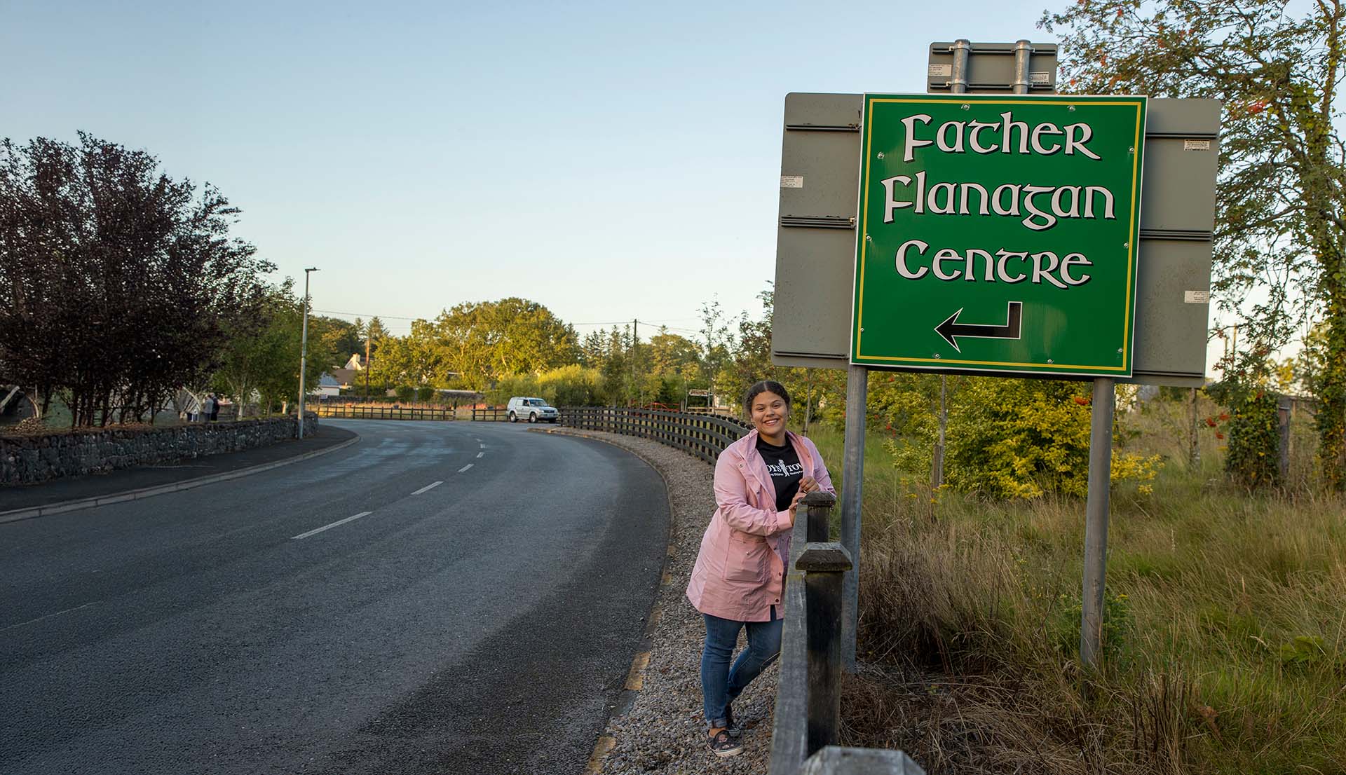 Roadside signpost pointing to Father Flanagan Centre with guest posing.